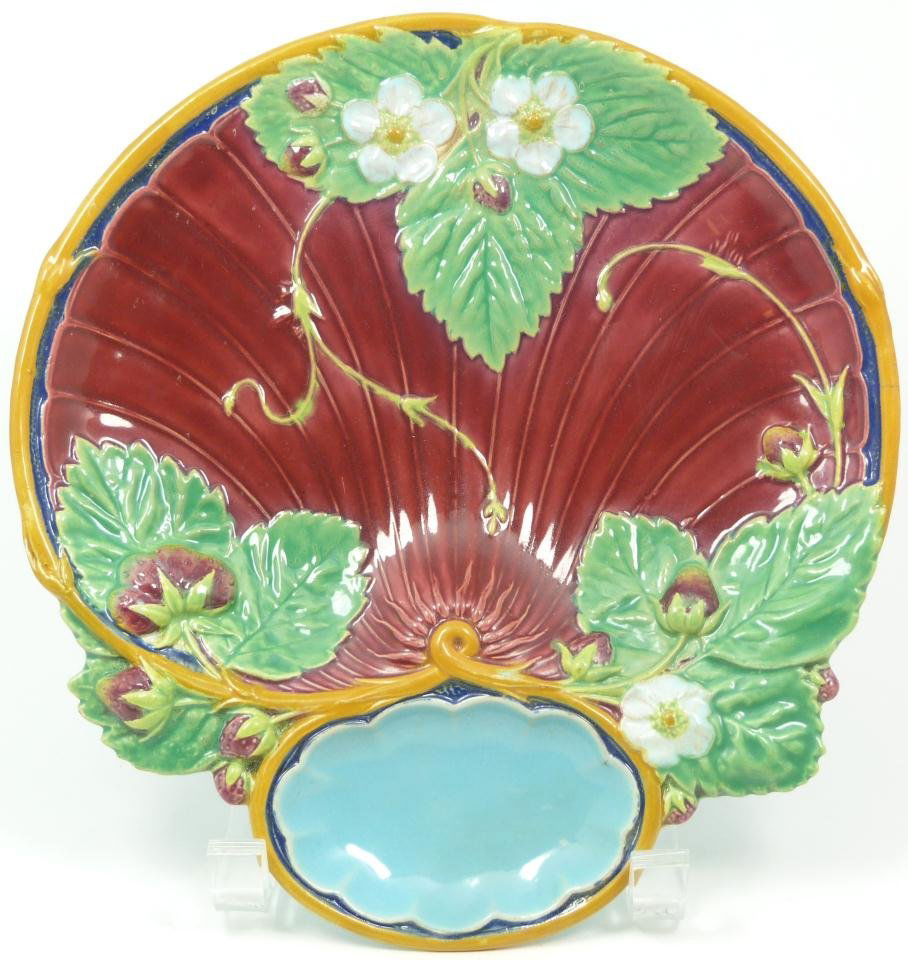 ANTIQUE MINTON MAJOLICA STRAWBERRY DISH: Antique Minton Majolica earthenware strawberry dish. Has a shell shape with raised floral and strawberry designs throughout. Holds impressed mark with raised registration mark. Also has impressed 1330