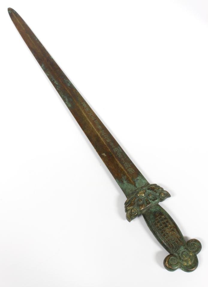 18th CENTURY CHINESE BRONZE FOO DOG SWORD: Antique Chinese bronze ceremonial sword. Has foo dog face design to handle with etched fish to each side. Etched calligraphy to side of blade. 18th century. Measures 23" length (58.4cm).
