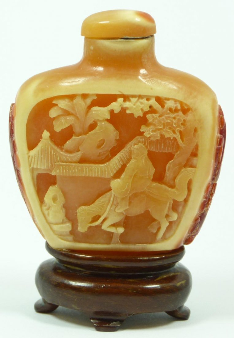 CHINESE HAND CARVED HORNBILL SNUFF BOTTLE: Chinese hand carved hornbill snuff bottle having relief courtyard scenes in relief design. Has raised Chih lung dragons to sides. Set to fitted wooden base. Measures 2 3/8" height x 2" width + 5/8" ba