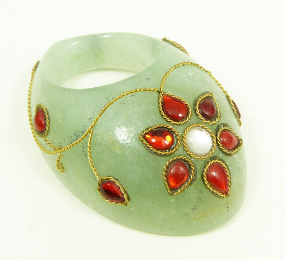 JEWELED CARVED JADE MUGHAL ARCHER'S RING: Jeweled hand carved jade Mughal archer's ring having a gold wired floral overlay design with carved ruby stones completing the design. Measures 2 1/8" length x 1 1/2" width (5.4cm x 3.8cm). Total weig