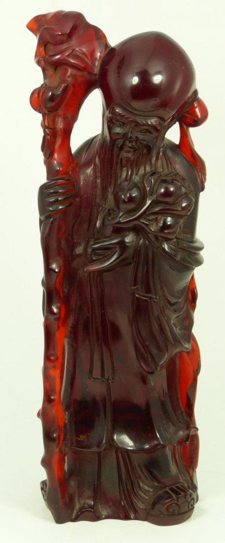 19th/20th C CHINESE CARVED CHERRY AMBER SHOU XING: Antique Chinese carved cherry amber Shou Xing figure. He is holding wooden staff with hanging gourd to right hand and peaches on branches to left. Measures 13 5/8" height (34.6cm). Total weight of 204