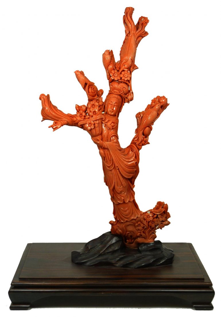 PALATIAL CHINESE RED CORAL CARVING OF QUAN YIN: Massive hand carved Chinese Red Coral figure depicting Guan Yin with four birds. Finely carved throughout with stunning detail with relief carving throughout. Includes fitted wooden display stand. Mea