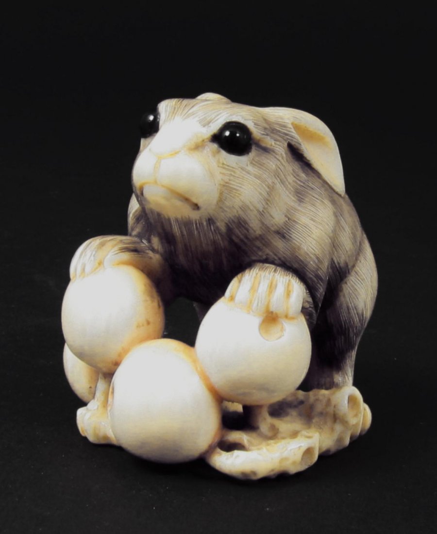 JAPANESE HAND CARVED IVORY RABBIT NETSUKE SIGNED: Fine Japanese hand carved ivory rabbit netsuke figure having inlaid black enamel eyes. Depicts a rabbit with branch and peaches. Meticulous attention to detail, down to the texture of the rabbit's fur