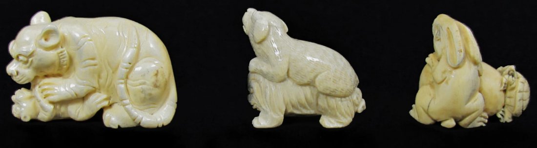 3 CARVED CHINESE IVORY NETSUKE ANIMAL FIGURES: 3 Japanese hand carved ivory netsuke figures depicting animals. Lot includes a tiger playing with a cub, a dog sitting on the back of a foo dog and an egg with rabbit and turtle. Largest approx. 1 7/8