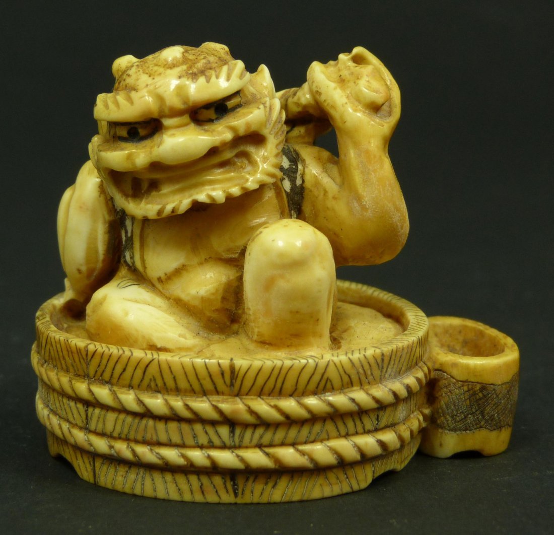 JAPANESE CARVED IVORY ONI NETSUKE FIGURE SIGNED: Antique Japanese hand carved ivory oni netsuke figure. The demon is depicted humorously taking a bath in a tub of water. Signed Youguang to bottom. 19th century. Measures 1 5/8" height (4.1cm). Total 