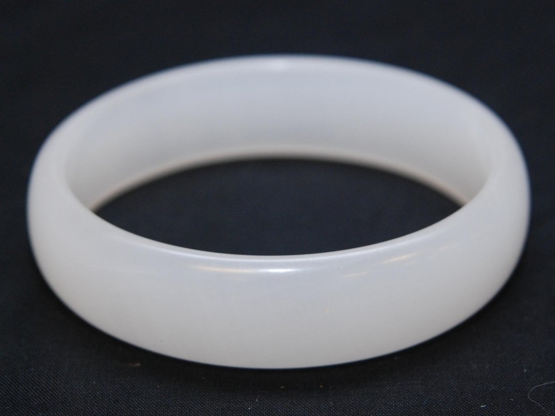 CHINESE CARVED IMPERIAL WHITE JADE BANGLE BRACELET: Chinese finely carved Imperial white jade bangle bracelet having domed exterior and flat interior. Has even mottled white jade tone. Measures 3 7/8" diameter (9.8cm). Fits wrist approx. 3 1/4" diamete