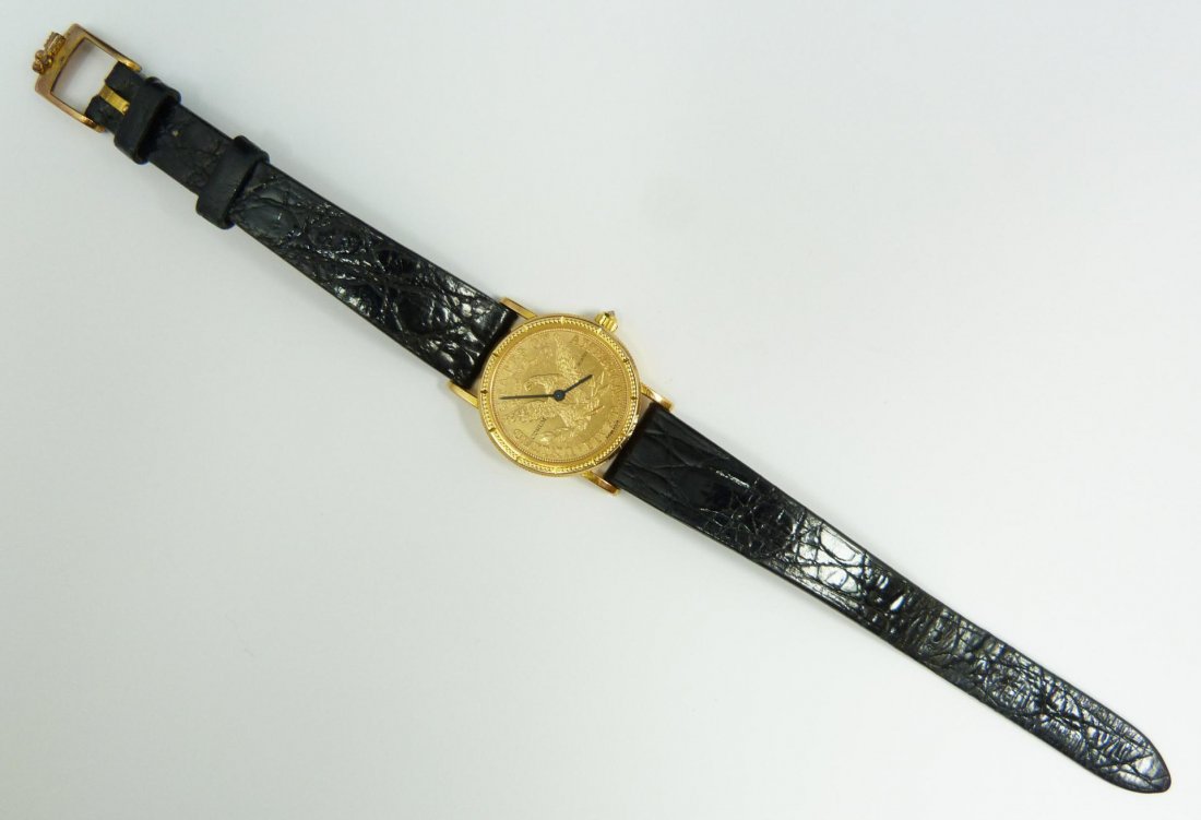 LADIES CORUM 1887 $5 LIBERTY GOLD COIN WATCH: Striking ladies Corum 1887 Five Dollar Liberty Head gold coin watch. Face shows the "tails" side of the coin depicting eagle with wings up. Has black hour and minute hands. Black enamel "CORUM QUARTZ"