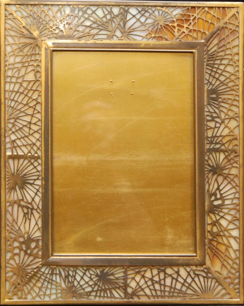 TIFFANY STUDIOS BRONZE 'PINE NEEDLE' FRAME: Tiffany Studios, New York bronze 'Pine Needle' frame having glass design to rim. Marked TIFFANY STUDIOS NEW YORK 918 E to verso. Includes Tiffany & Co. dust cover bag. Measures 12" height x 9 3/4" wid