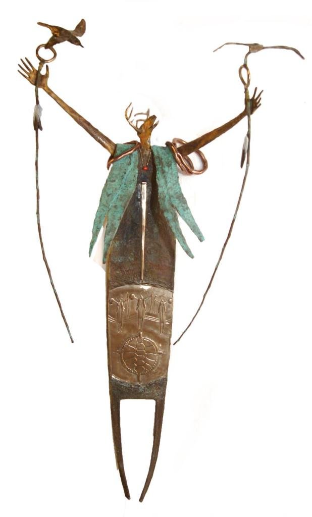 BILL WORRELL 'THE ETERNAL GUARDIAN' BRONZE: Bill Worrell (AMERICAN. 20th century) bronze sculpture depicting a standing Shaman with deer head holding up staffs in each hand with birds. He is wearing an apron with 2 raised Shamans and turtle she