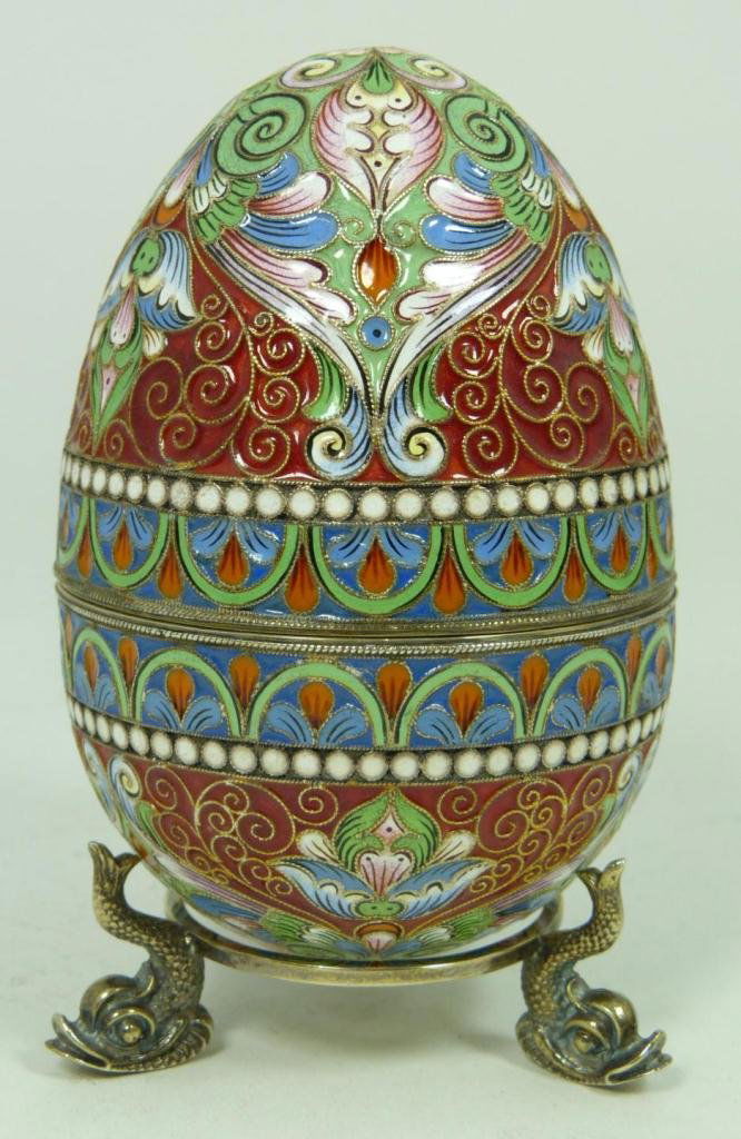 RUSSIAN SILVER ENAMELED EGG: Russian silver enameled egg box having elegant scrolled floral design. Gold wash interior. Includes stand with three figural fish feet. Piece holds workmaster marks. Holds 88 silver purity mark with M