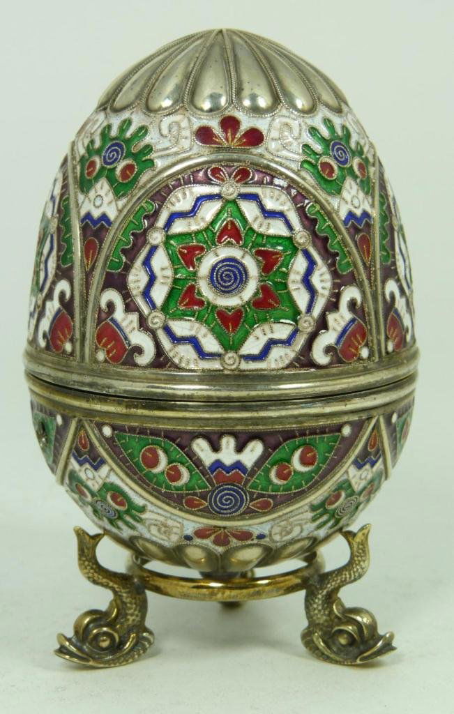 RUSSIAN SILVER ENAMELED EGG WITH STAND: Finely crafted Russian silver egg with multicolor enameled design throughout. Has Cabochon garnet to end. Workmaster marks, town marks and 84 silvery purity mark. Includes silver figural fish footed s