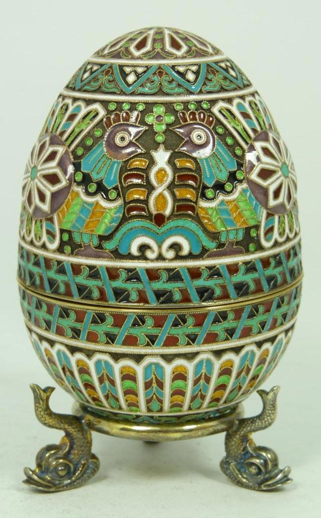RUSSIAN SILVER ENAMELED EGG: Russian silver enameled egg box having elegant scrolled design with chickens and pinwheels. Gold wash interior. Includes stand with three figural fish feet. Piece holds Cyrillic Pavel Akimov Ovchinnik