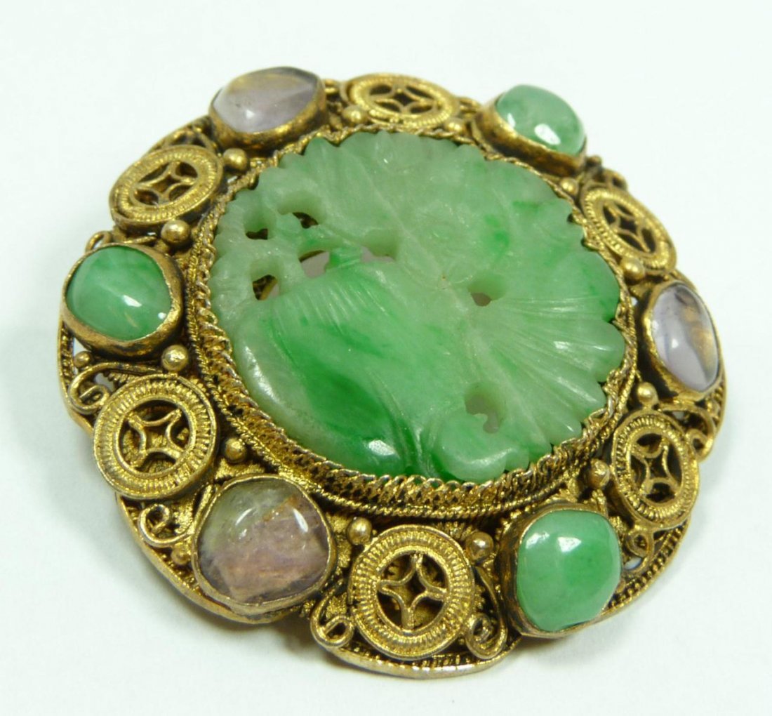 A CHINESE VERMEIL SILVER & JADEITE PIN: A beautiful ladies Chinese vermeil silver pin holding a round reticulated jadeite plaque depicting a bat with peach. Translucent mottled white to apple green jadeite colors. Silver frame jeweled with