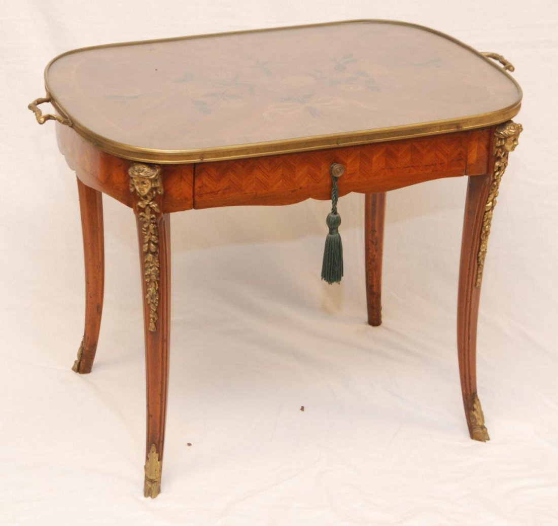 A FRENCH MARQUETRY TABLE w DORE APPLIQUE: A French marquetry wood table having floral designs throughout. Clad with Dore bronze applique to legs depicting the face of a woman with ribbons and flowers running down the side of the leg. Figural 