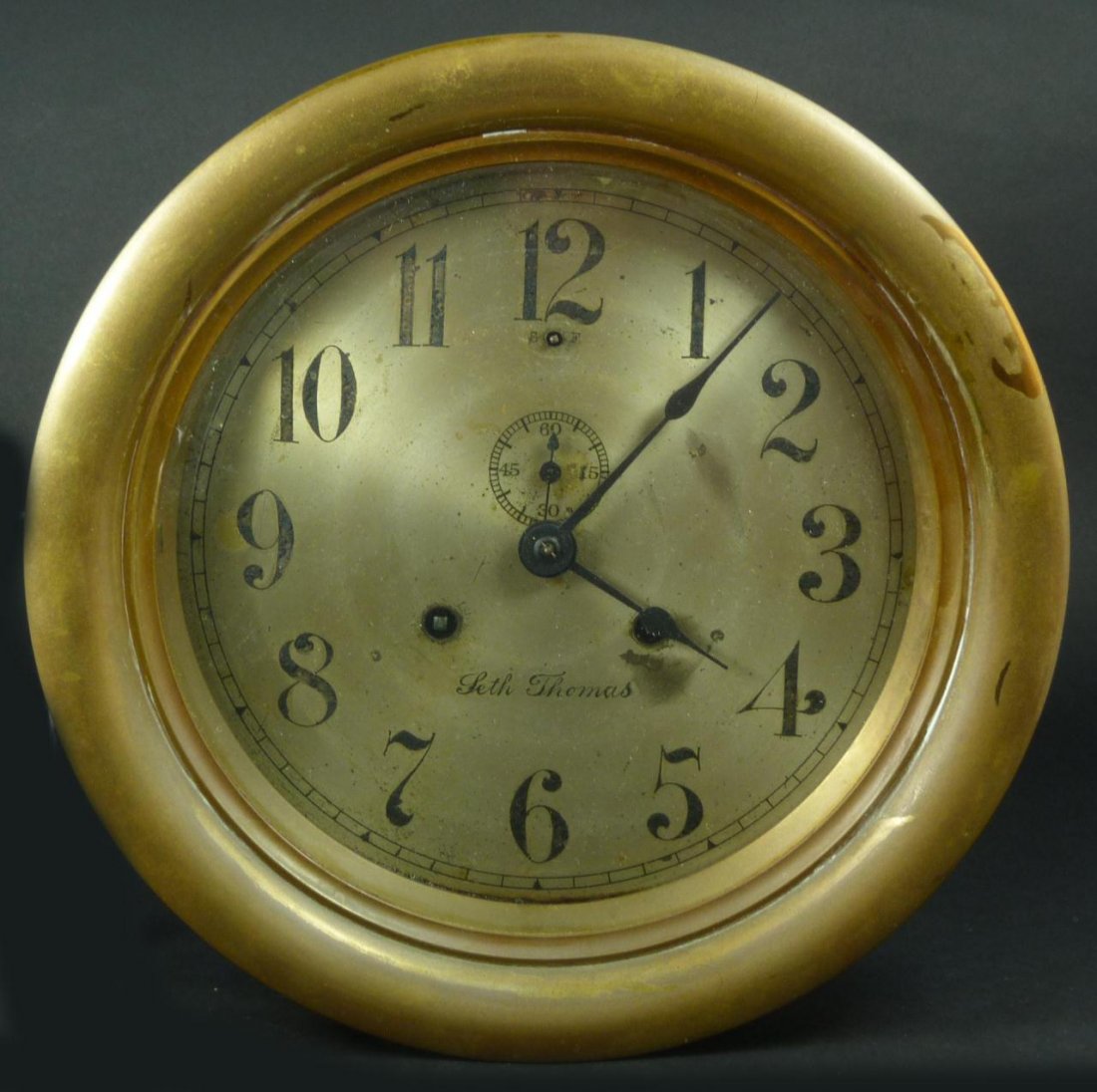SETH THOMAS BRASS SHIP'S CLOCK: A Seth Thomas brass ship's bell. Has silvered face with black Arabic Numerals and notches. Black hour, minute and sub-second hand. Has a hinged locking cover with glass screen. Has three holes for bol