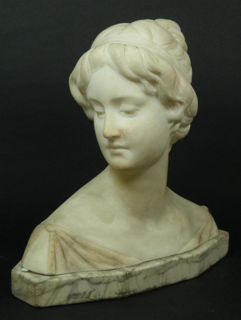 CARVED MARBLE BUST OF A WOMAN SIGNED: A carved marble bust depicting a woman. Holds manufacturers marks to bottom. Signed to verso. Measures 8 1/4" height x 9 1/2" width + 1" base height (20.9cm x 24.1cm + 2.5cm). Total weight of 4.58 kil