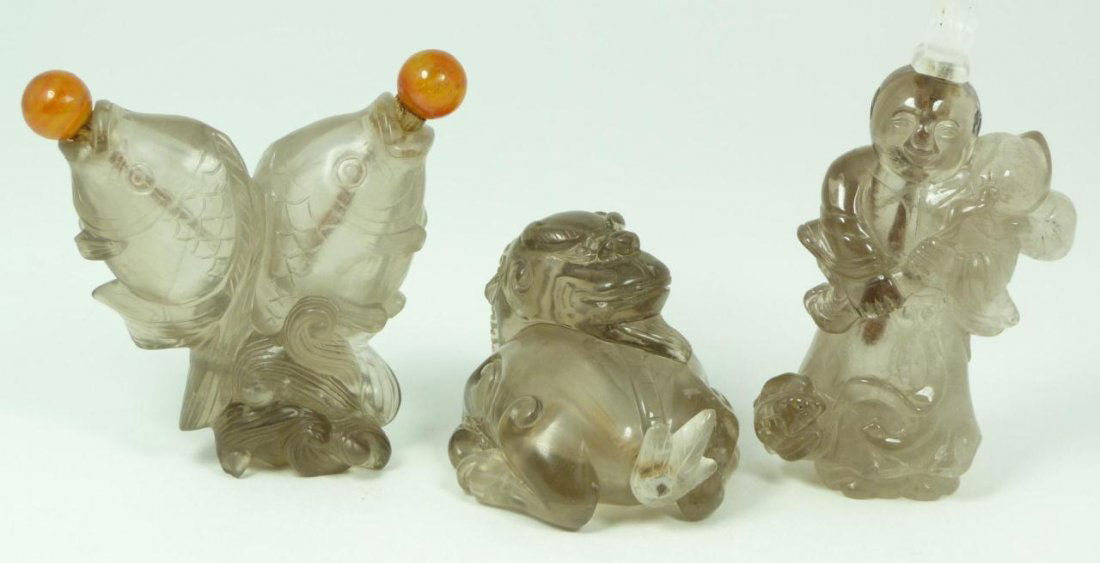 3 CHINESE CARVED SMOKEY QUARTZ SNUFF BOTTLES: 3 antique Chinese relief carved smokey quartz figural snuff bottles. One depicting seated foo lion, child with peaches and bats and two jumping fish. 19th/20th century. Largest measures 3 1/2" height