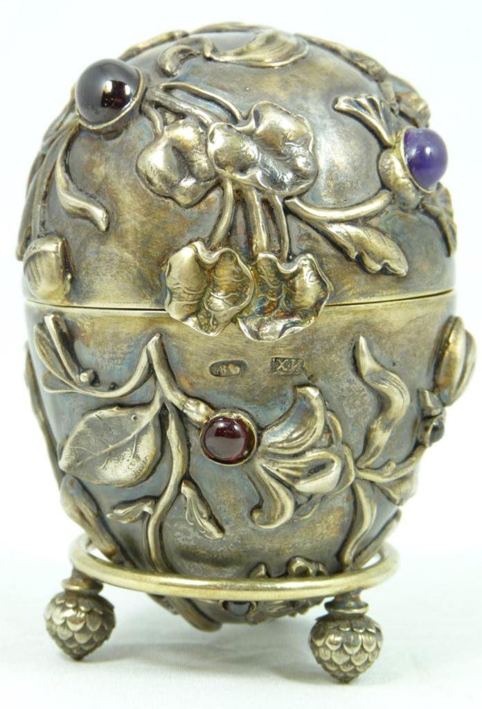 RUSSIAN SILVER JEWELED INSECTS EGG: Russian silver egg. Has intricate raised design depicting bees with flowers. Mounted with Cabochon garnets throughout with one sapphire. Gold wash interior. Has Ivan Petrovich Khlebnikov workmaster ma