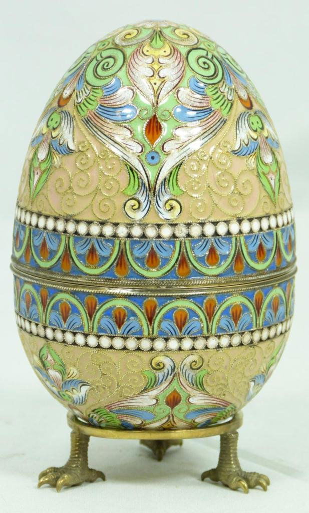 RUSSIAN SILVER ENAMELED EGG BOX w STAND: Russian silver enameled egg box having multicolor scrolled floral design. Gold wash interior. Includes stand with three figural eagle's feet. Piece holds Fedor Ruckert workmaster marks. Holds 88 silve