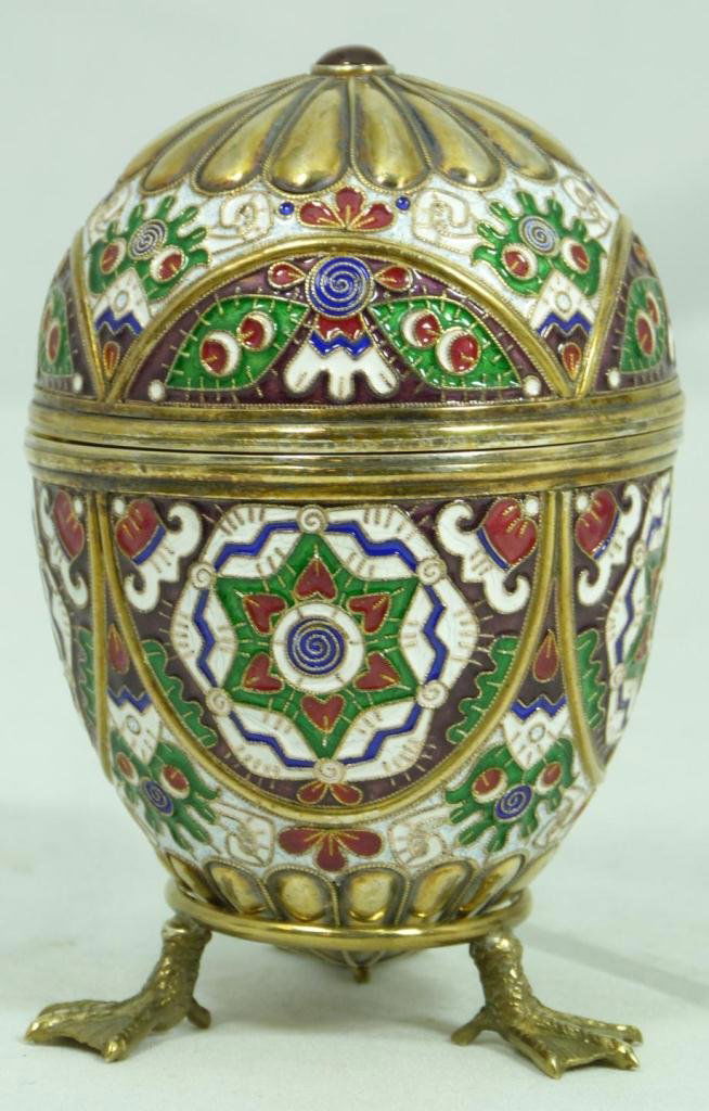 RUSSIAN SILVER ENAMELED EGG WITH STAND: Finely crafted Russian silver egg with multicolor enameled design throughout. Has Cabochon ruby to end. Workmaster marks, town marks and 84 silvery purity mark. Includes silver figural tripod swan foo