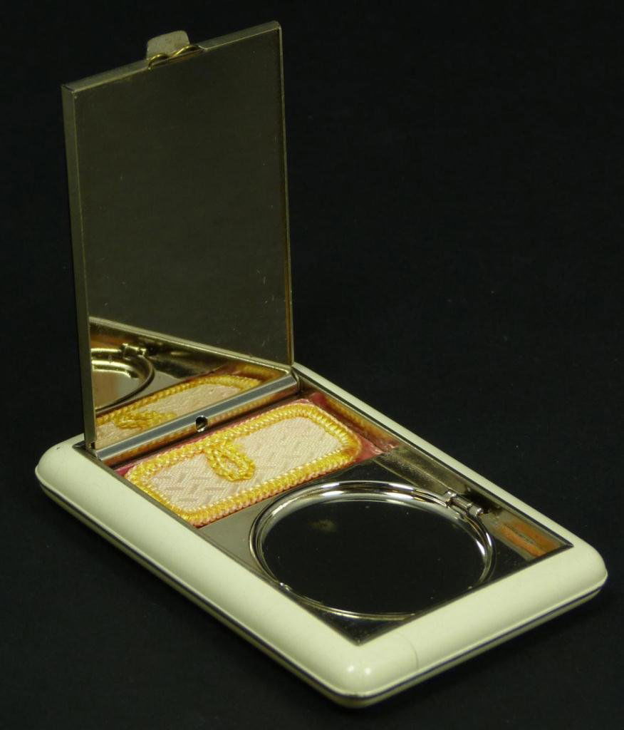 ART DECO BAKELITE & CORAL APPLIQUE COMPACT: An art deco bakelite compact. Has applique carved red coral floral plaque to top. Silver tone interior with mirror. Measures 3" length x 2 1/4" width x 5/8" depth (7.6cm x 5.7cm). Total weight of 77 g