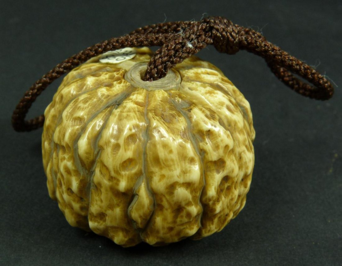 CARVED IVORY JAPANESE NETSUKE SIGNED SHODO: A Japanese carved ivory netsuke depicting Hotei and Fukurokuju playing games of Go. They are placed inside of a pumpkin that opens up to reveal the scene. Signed Shodo to inside of pumpkin. Includes w