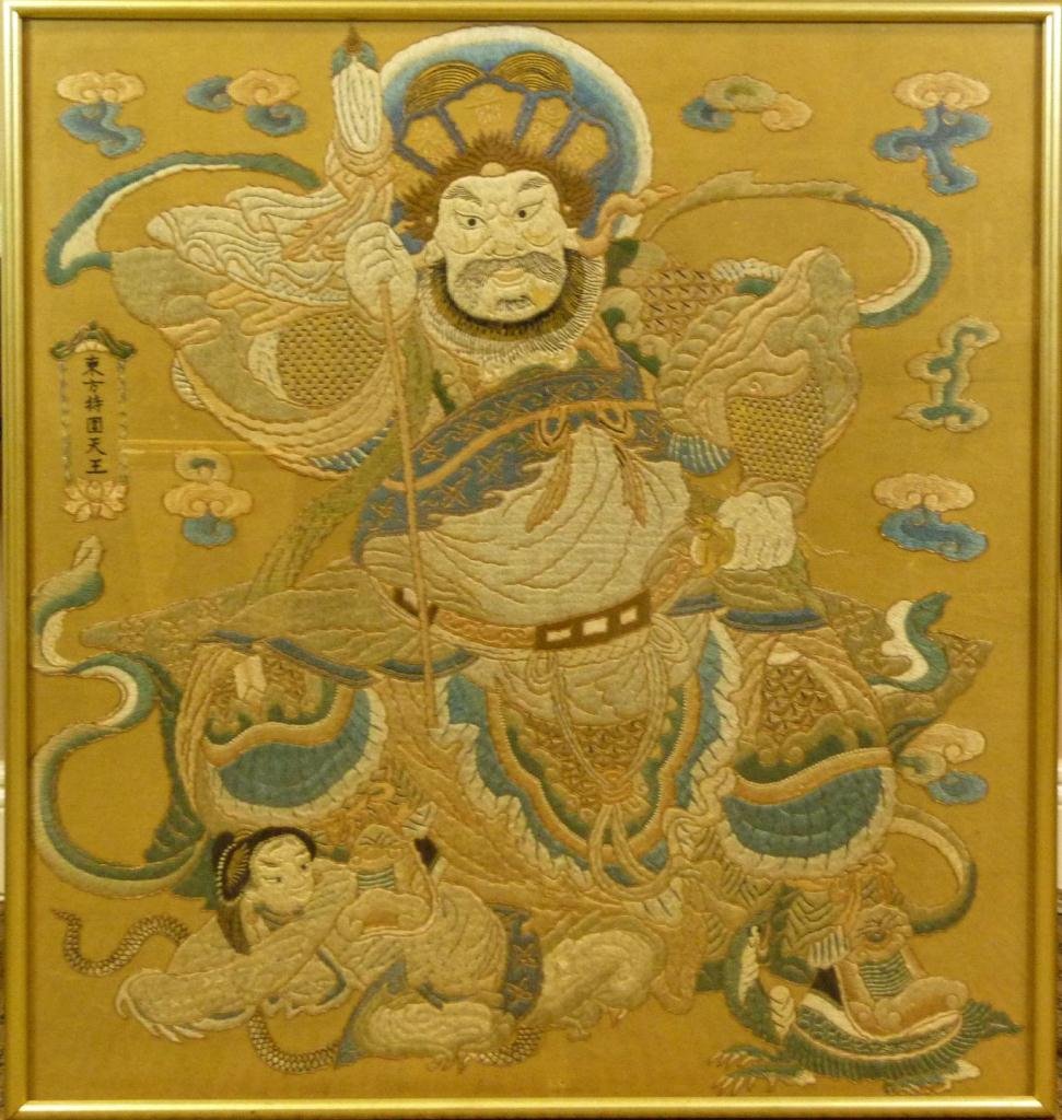 CHINESE WOVEN SILK DEPICTING OF WARRIOR: A Chinese woven silk depiction of warrior with blade, dragon and attendant. Mounted in gilded frame behind glass screen. Measures 34" height x 31 1/2" width + 7/8" frame (86.3cm x 80cm + 2.2cm).