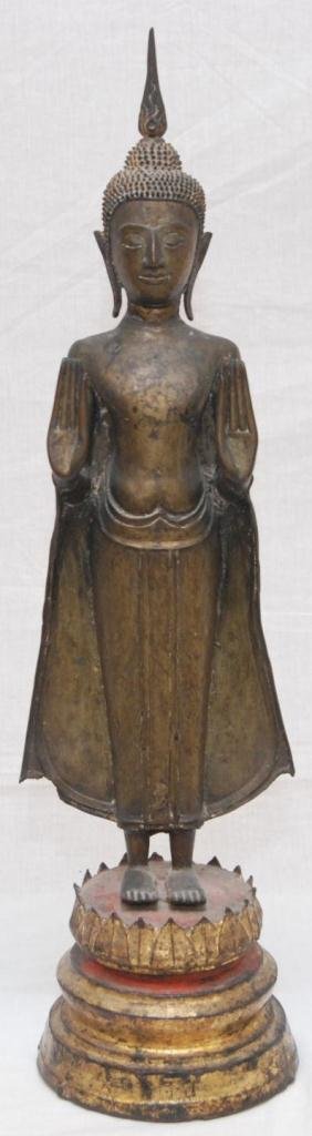 16th CENTURY THAI BRONZE STANDING BUDDHA FIGURE: An antique Thai bronze sculpture depicting a standing Buddha over gilded wooden lotus blossom form base. Circa mid Kingdom of Ayutthaya period (1350–1767). Measures 22" height + 5 1/8" base height (