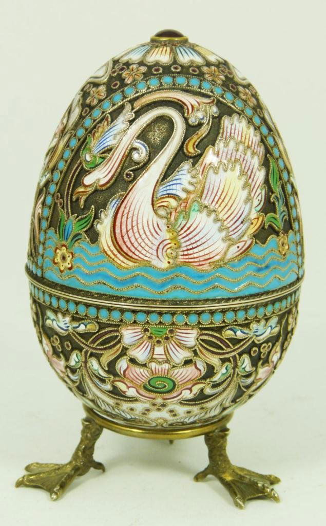 RUSSIAN SILVER ENAMELED SWANS EGG: Russian silver enameled egg box having elegant multicolor design swans. Gold wash interior. Includes stand with three figural duck feet. Piece holds Cyrillic Pavel Akimov Ovchinnikov workmaster marks.