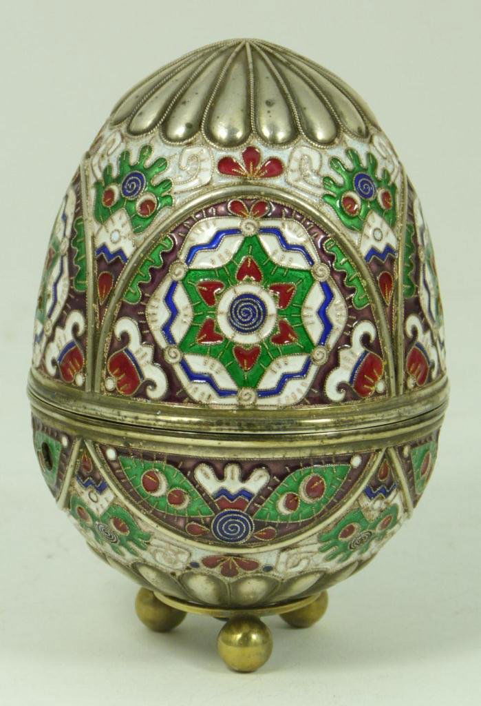 RUSSIAN SILVER ENAMELED EGG WITH STAND: Russian silver egg with multicolor enameled design throughout. Has Cabochon ruby to end. Holds workmaster marks, town marks and 84 silvery purity mark. Includes silver figural fish footed stand. Egg m
