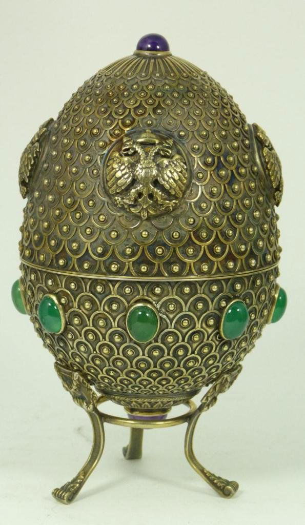 LARGE RUSSIAN SILVER JEWELED EGG: Large Russian silver egg having a beaded feather design throughout. Top half holding four raised Double Headed Eagle coat of arm designs. Egg holds two cabochon cut sapphire jewels to top and bottom.