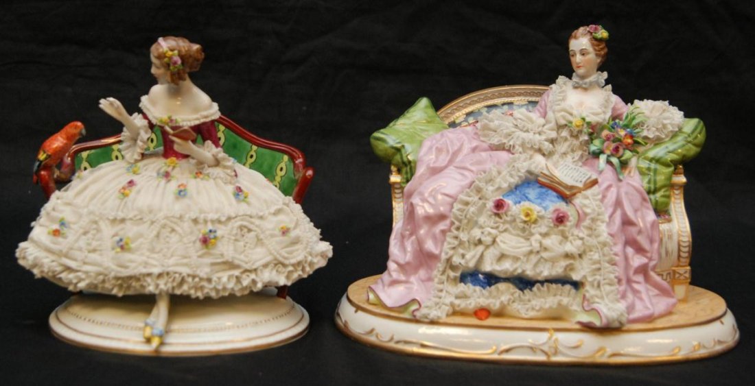 2 GERMAN PORCELAIN FIGURES OF WOMEN ON SETEE: Pair of German hand painted porcelain figures depicting women sitting on a settee. Each having a lace porcelain design with figural flowers. One holding a crown mark to bottom. 19th/20th century. Larg