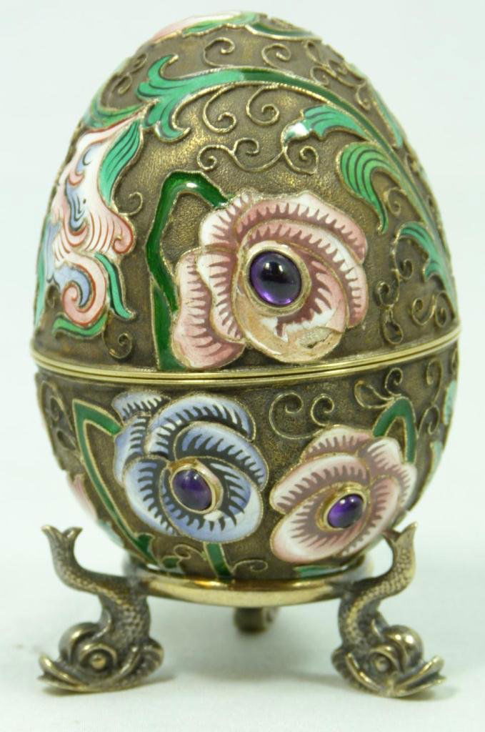 RUSSIAN SILVER ENAMELED JEWELED FLORAL EGG: Russian silver enameled egg box having multicolor floral design. 6 cabochon cut sapphire jewels mounted to center of pink and violet enameled flowers. Gold wash interior. Includes figural fish silver