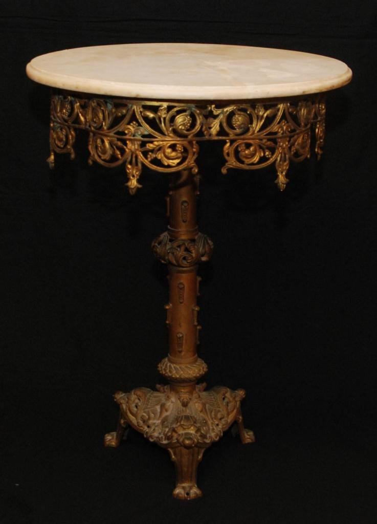 OLD BRASS MARBLE TOP PARLOR TABLE: Old brass table with a round white marble top and reticulated floral scroll skirt. Three figural beast head feet. 19th/20th century. Measures 28 1/2" height x 21 1/8" diameter (72.3cm x 21.1cm). Total