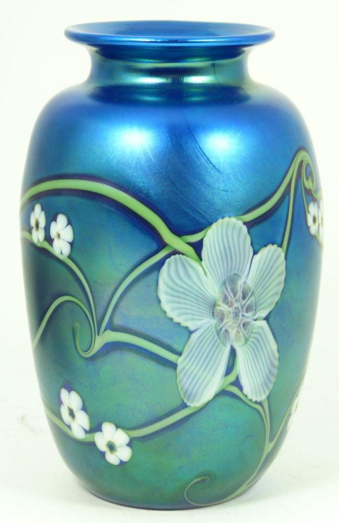 ORIENT & FLUME IRIDESCENT ART GLASS FLORAL VASE: Orient & Flume iridescent art glass vase having a floral design over cobalt ground. Bottom holds etched company marks and dated 1984. Also artist signed to bottom. Has original label to bottom. Measur