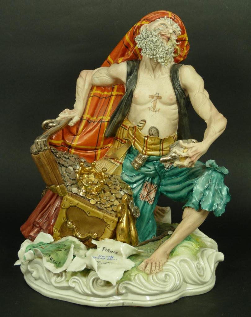 CAPODIMONTE 'THE PIRATE'S TREASURE CHEST' FIGURE: Capodimonte Italian porcelain figure depicting a pirate with a treasure chest filled with gold coins. The front of the sculpture's base has a treasure map. Titled 'The Pirate's Treasure Chest' or 'Pir