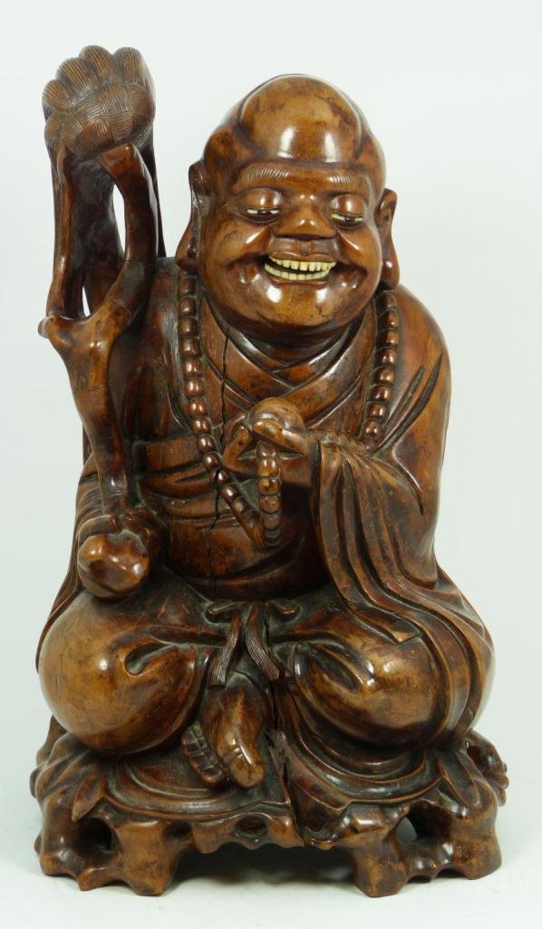 ANTIQUE CHINESE CARVED WOOD HOTEI FIGURE: A Chinese hand carved wooden figure depicting seated Hotei wearing beaded necklace and holding wooden tasseled wand. Wood form base. Has carved and inlaid ox bone teeth and eyes. Measures 15" height (