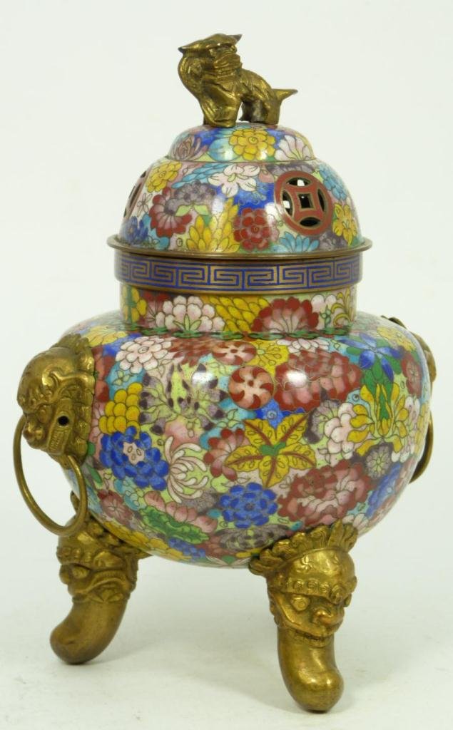 CLOISONNE TRIPOD INCENSE BURNER W/ FOOD DOG FINIAL: Antique Chinese cloisonne censer with multicolored floral design throughout with stylized ling zhi band on neck. Figural foo dog head handles with rings and figural foo dog finial on cover. Late Qing 