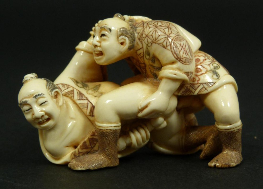 CARVED IVORY EROTIC NETSUKE OF TWO MEN SIGNED: Hand carved Japanese ivory erotic netsuke figure depicting two men. Each has polychromed robes depicting symbols and flowers. Signed on bottom. Measures 2" length x 1 3/8" height (5.1cm x 3.5cm). Tota