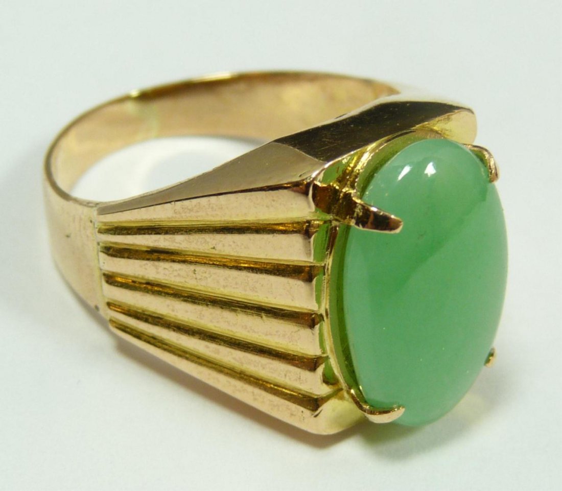 18K YG GREEN JADEITE CABOCHON SOLITAIRE RING: A men's 18k yellow gold solitaire ring holding an oval cabochon cut green jadeite stone approx. 16.3mm x 10.3mm x 3.8mm. Ring size 10. Total weight of 6.6dwt.