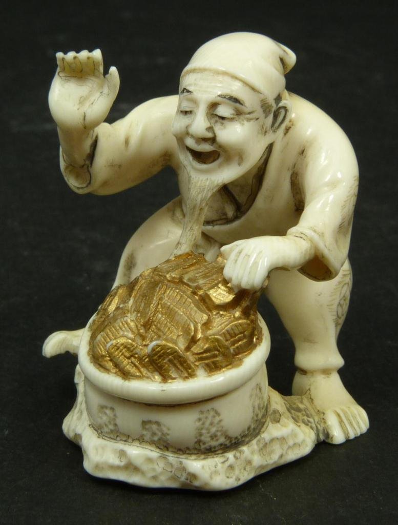 JAPANESE IVORY SCUPTURE OF MAN WITH GOLD POT: Japanese hand carved ivory Netsuke figure depicting a man with a pot full of gold. Calligraphy signature to bottom. Measures 1.75in Height. Weighs 21g.