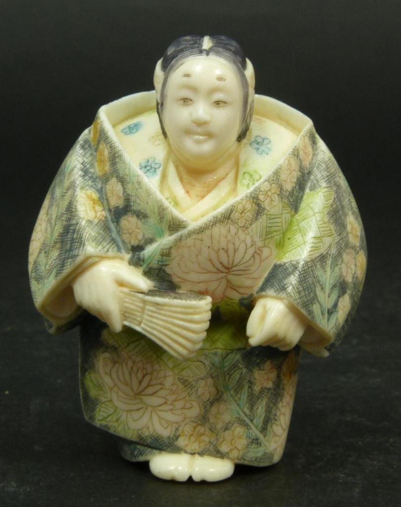 JAPANESE CARVED IVORY MAIDEN NETSUKE: Japanese carved and polychromed ivory netsuke depicting standing maiden with fan. Red calligraphy signature to bottom. Measures 2in Height. Weighs 42g.