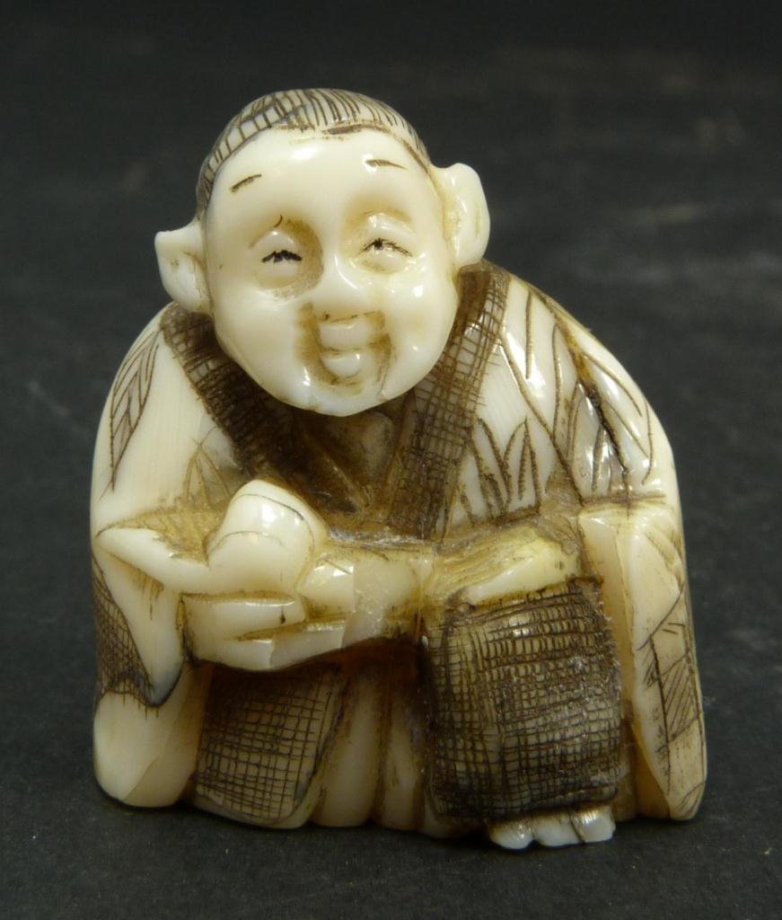 JAPANESE CARVED IVORY NETSUKE OF MAN: Japanese carved ivory netsuke figure depicting a man with fruit. Etched calligraphy signature to bottom. Measures 1 3/8in Height. Weighs 19g.