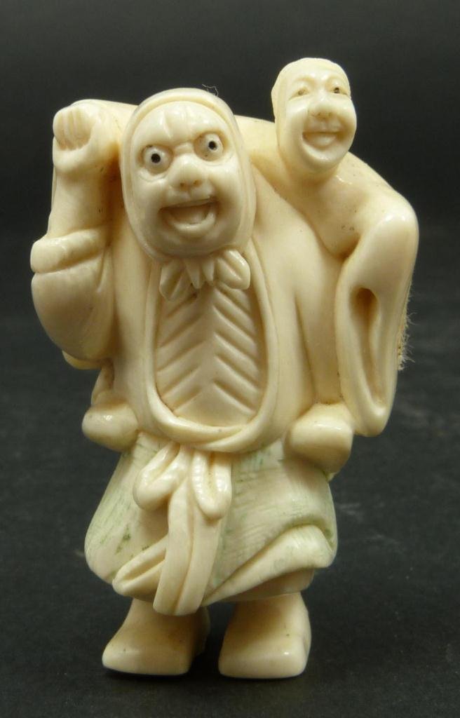 JAPANESE CARVED IVORY NETSUKE LOHAN GROUP: Japanese carved and polychromed ivory netsuke depicting Lohan with attendant. Etched calligraphy signature to bottom. Measures 2 1/8in Height. Weighs 33g.