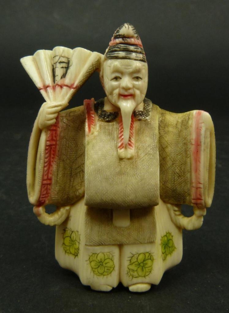 JAPANESE CARVED IVORY KABUKI THEATER NETSUKE: Japanese carved and polychromed ivory netsuke figure depicting a Kabuki theatre actor holding fan. Etched calligraphy signature to back of left leg. Measures 2 1/8in Height. Weighs 30g.