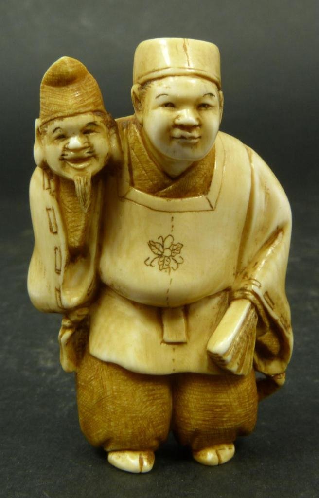 JAPANESE CARVED IVORY NETSUKE OF PUPPETEER: Japanese hand carved ivory figure depicting puppeteer . Etched calligraphy signature to bottom. Measures 2 1/8in Height. Weighs 24 grams.