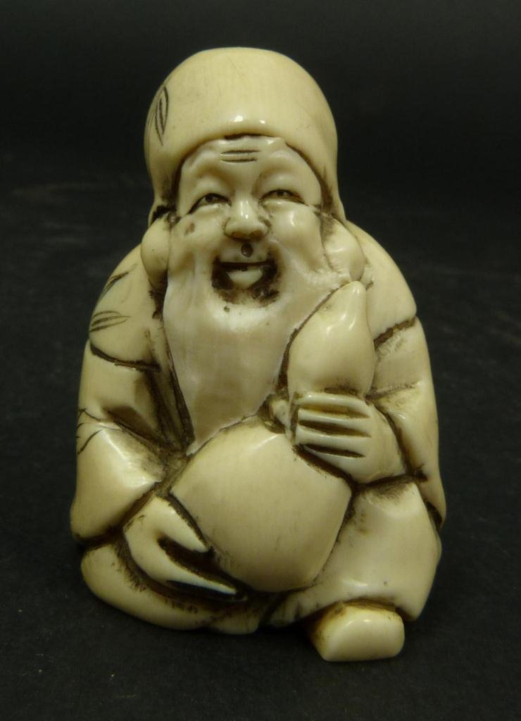JAPANESE CARVED IVORY NETSUKE OF WISE MAN: Japanese carved ivory netsuke figure depicting a seated wise man holding Hulu double gourd. Etched calligraphy signature to bottom. Measures 1 5/8in Height. Weighs 24g.