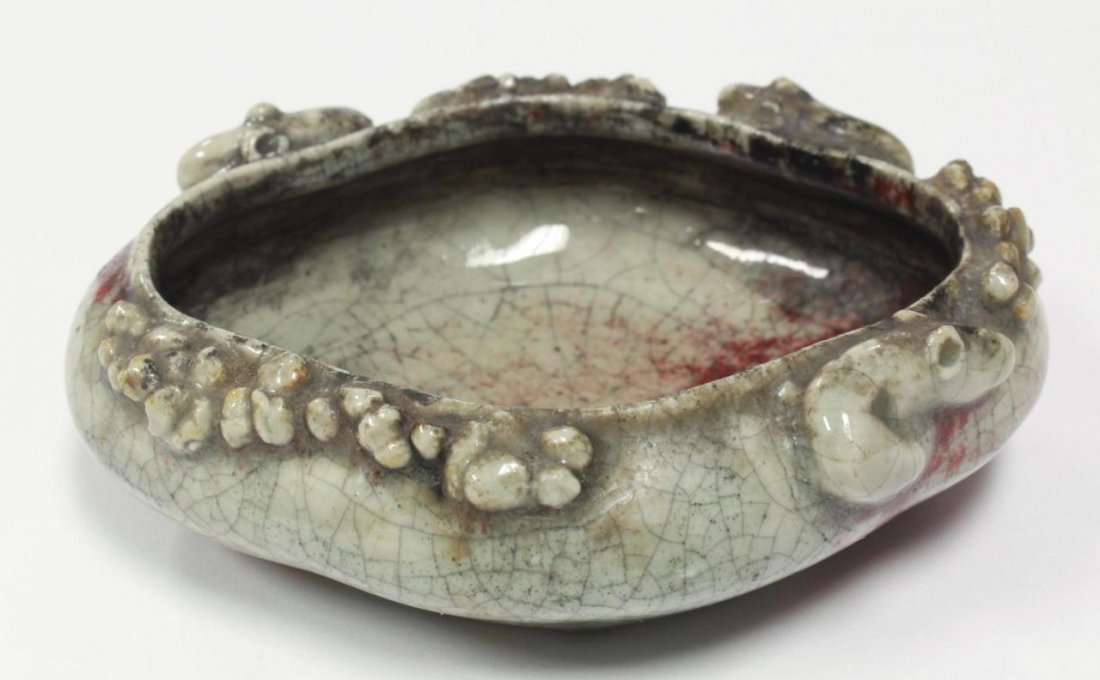 CHINESE QING DYN. GLAZED CHI-DRAGON BRUSH WASHER: Chinese Qing Dynasty ceramic brush washer, grayish celadon crackle glaze suffused with oxblood crimson, base left unglazed. Molded in high relief with three Chi-dragons encircled around the rim.
