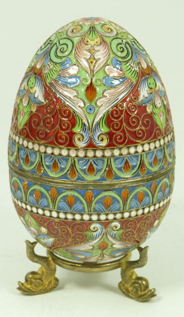 RUSSIAN SILVER ENAMELED EGG WITH STAND: Russian silver enameled egg box with elegant scrolled floral design and gold wash interior. Includes stand with three figural fish feet. Piece holds double headed eagle marks. Holds 88 silver purity m