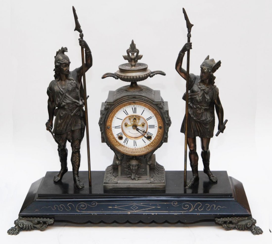 NEW HAVEN SPELTER METAL FIGURAL MANTEL CLOCK: Antique New Haven spelter metal figural warriors with spears mantel clock. White enameled face with black Roman numerals. Black enameled base. Late 19th to early 20th century. Measures 20" height x 23